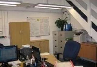 Bright office area with workstations, whiteboards, and filing cabinets.