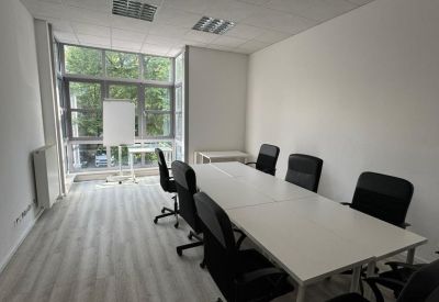 Meeting room with a long white table, black chairs, and a flipchart.