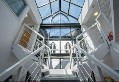 Spacious atrium area featuring a symmetrical white staircase and glass ceilings.