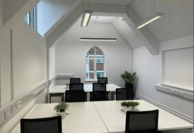 Bright office space with white desks and an arched gothic-style window.