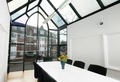 Modern meeting room with a white table and large slanted glass roof panels.
