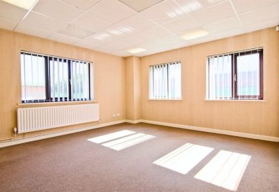 Well-lit open plan office suite featuring multiple windows with vertical blinds and wall-mounted heaters.