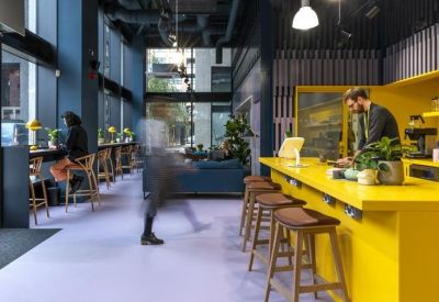 Vibrant cafe area featuring a bright yellow counter, wooden stools, and purple flooring.