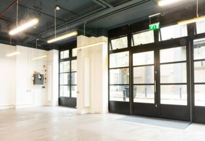 Bright lobby entrance with large black-framed glass doors and industrial lighting.