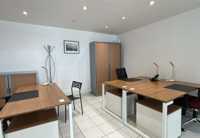 Private office space with three wooden desks, black ergonomic chairs, and a tall storage cabinet.