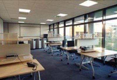 Open-plan office space featuring modular desks and large windows for natural light.
