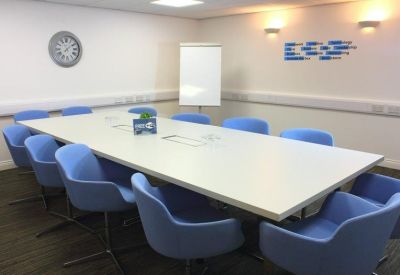 Bright meeting room with a large white table and blue chairs.