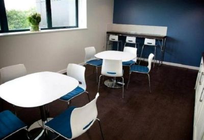Breakout area with white circular tables and blue-cushioned chairs.