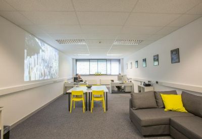 Spacious breakout area with a large grey sofa and yellow accent cushions.