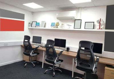 Modern workspace with ergonomic chairs, wood-finish desks, and a red feature wall.