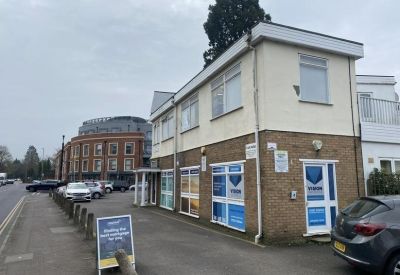 Side angle of the commercial property showing ground floor windows with blue signage and a street view.