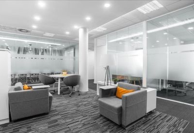 Spacious open-plan lounge with grey armchairs and orange accent pillows.