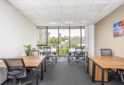 Spacious open-plan office with wooden desks and floor-to-ceiling windows.