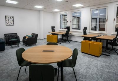 Spacious communal lounge and workspace with a round wooden table and yellow storage units.