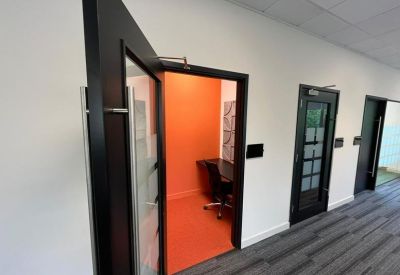 Private orange phone booth or quiet workspace with a small desk and chair.