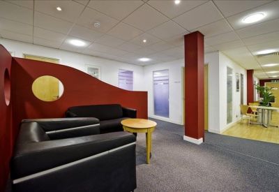 Informal breakout area with a curved red wall and black leather sofas.