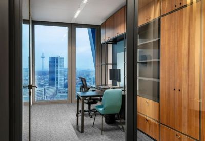 Bright corner office with teal chairs and expansive city skyline views.