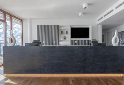 Sleek black reception desk in a bright, modern lobby with integrated wall shelving.