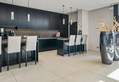 Modern kitchen and breakout area with black cabinetry and high-top seating.