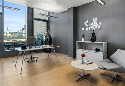 Private executive office with a minimalist desk and a grey lounge chair by the window.