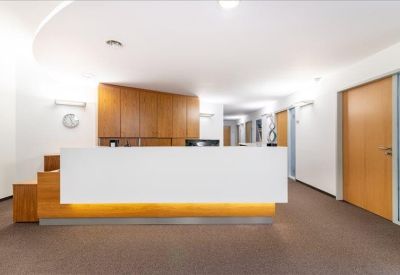 Modern white reception desk with warm under-cabinet lighting and wood paneling.