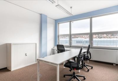 Bright corner office with three workstations and large windows.