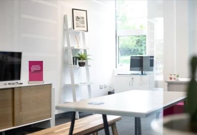 Bright breakout space with a white table, wooden bench, and ladder shelving.