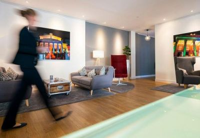 Spacious communal lounge area with modern grey sofas and vibrant wall art.