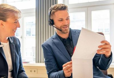 Two professionals reviewing documents in a bright, modern office setting.