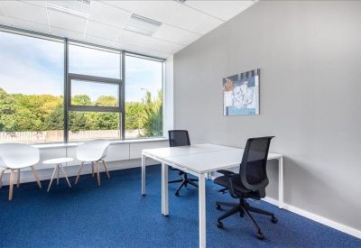 Minimalist private office with white desks, black chairs, and a blue carpet.