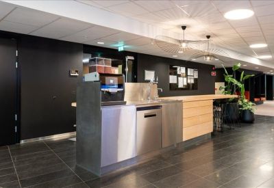 Modern kitchenette and break area with wood cabinetry and professional coffee equipment.