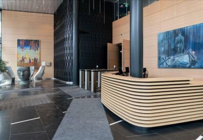 Spacious reception lobby featuring a curved wood-slatted desk and contemporary artwork.