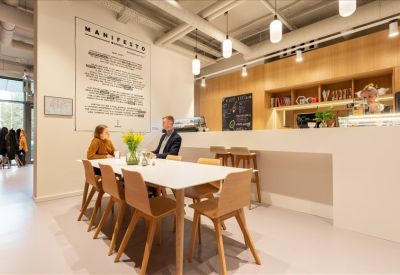 Contemporary breakout space with a large white table, wooden chairs, and cafe counter.