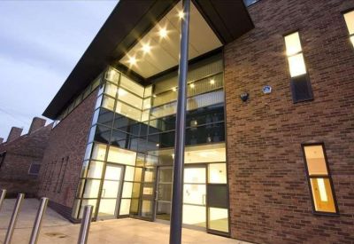 Bright glass-fronted building entrance with illuminated interior and metal bollards.