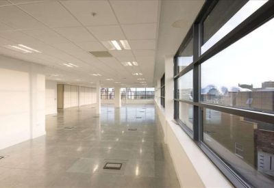 Spacious open-plan office floor with polished tiles and large windows.