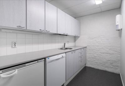 Clean, modern kitchen area with white cabinetry and grey flooring.
