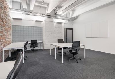Bright private office with white walls and dual workstations.