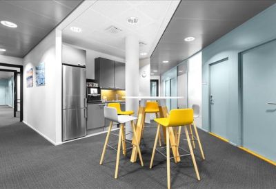 Modern communal breakout area with yellow bar stools and a sleek kitchenette.
