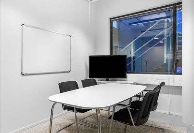 Minimalist meeting room with a white table, whiteboard, and plush rug.