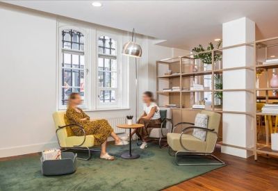 Casual meeting area with mid-century style armchairs and a minimalist bookshelf.
