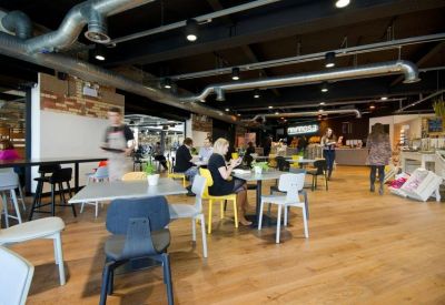 Bright on-site café with wooden floors and industrial-style ceiling ductwork.