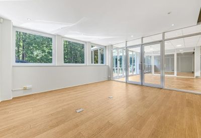 Bright office suite with wood flooring and views through large windows into a glass atrium.