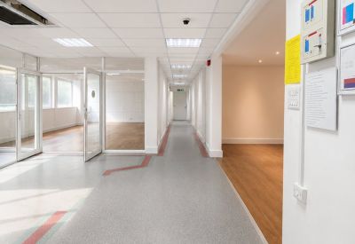 Bright white corridor with speckled grey flooring and glass office partitions.