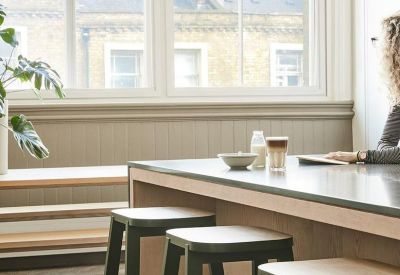 Light-filled communal dining area with wooden bar stools and large windows.