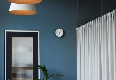 Meeting room with a long wood table, blue walls, and modern pendant lighting.