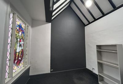 Unique private office featuring a vaulted ceiling with exposed black beams and stained glass window.
