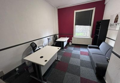Furnished office suite with white desks, grey seating, and a bold burgundy accent wall.