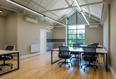 Bright meeting room with white tables, mesh chairs, and high ceilings with exposed beams.
