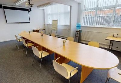 Professional meeting room featuring a long wooden conference table and projection screen.