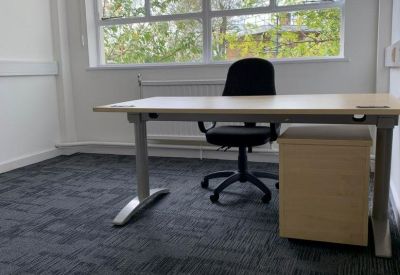 Private office space with a modern desk, black chair, and large windows.